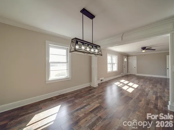 a view of an empty room with window and wooden floor