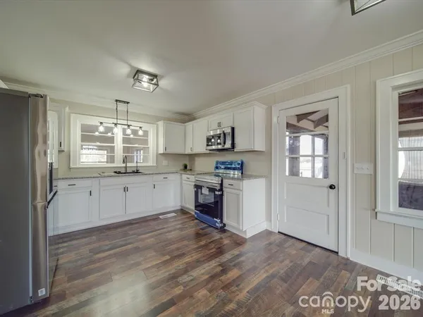 a kitchen with granite countertop white cabinets and stainless steel appliances