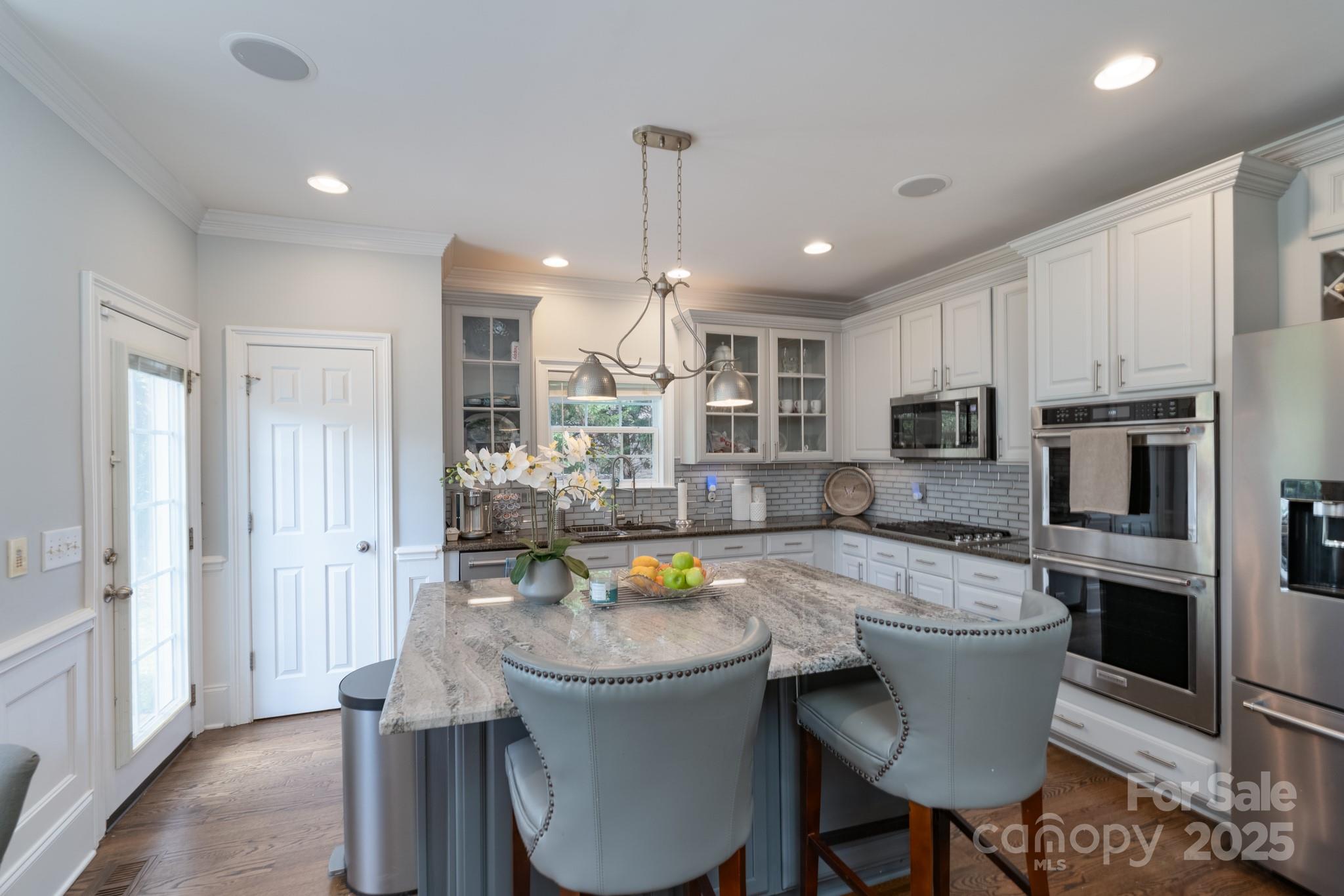 779 Fairway Point Drive Tega Cay, SC 29708 - Photo 12 of 48 a kitchen with a dining table chairs stainless steel appliances and cabinets