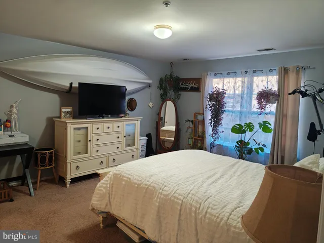 a bedroom with a bed and a flat tv screen on dresser