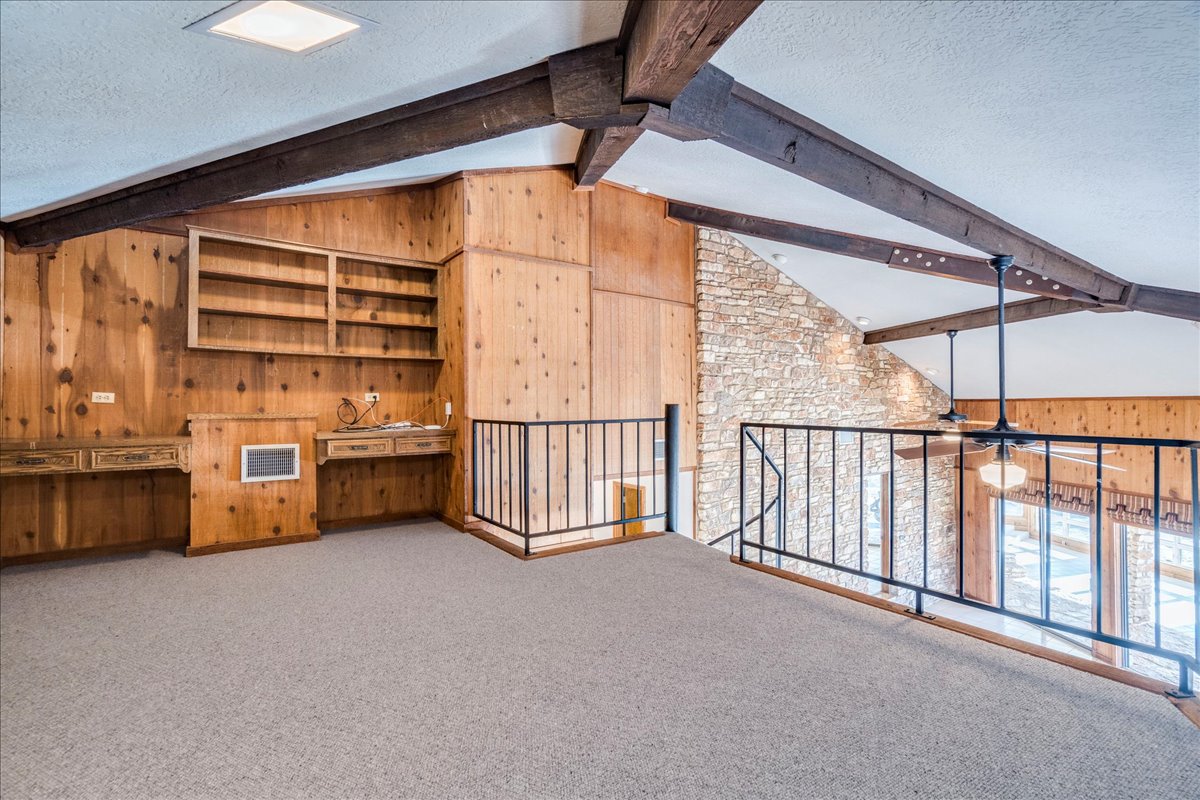 9763 Ranch Road 1623 Blanco, TX 78606 - Photo 18 of 40 Carpeted loft space featuring wood paneling, built-in shelving, and two built-in desks