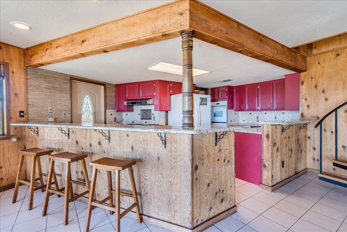 9763 Ranch Road 1623 Blanco, TX 78606 - Photo 27 of 40 a kitchen with stainless steel appliances kitchen island granite countertop a table chairs in it and wooden floors