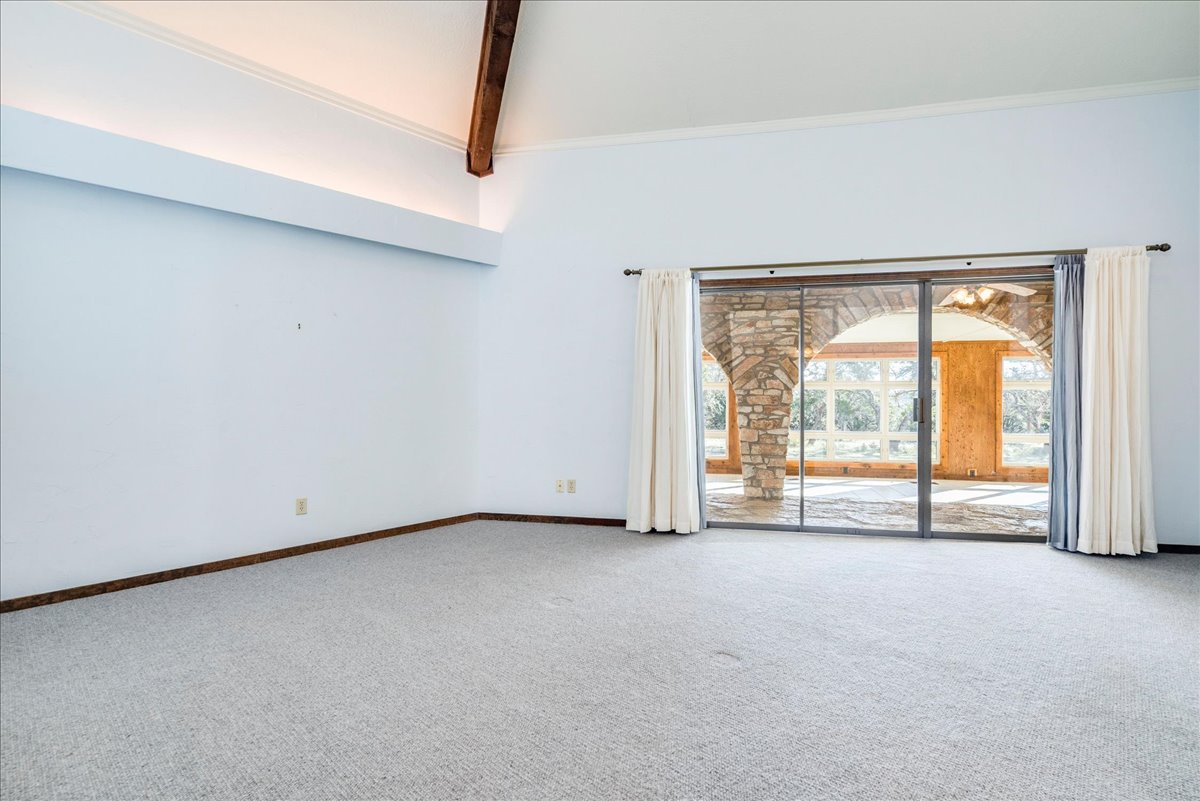 9763 Ranch Road 1623 Blanco, TX 78606 - Photo 28 of 40 Spacious interior room with light-colored carpeting, white walls, and a vaulted ceiling featuring a visible wood beam