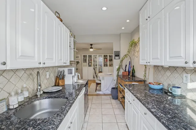 a kitchen with granite countertop a sink a stove and cabinets