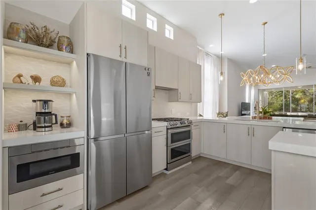 a large white kitchen with a refrigerator and wooden floor