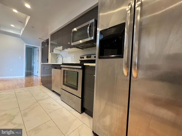 a kitchen with stainless steel appliances kitchen island granite countertop a refrigerator and a stove