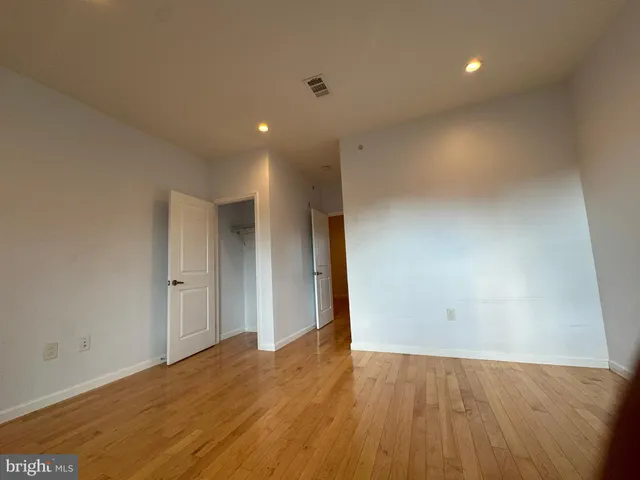 a view of an empty room with wooden floor and closet
