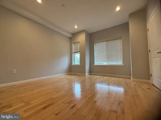 an empty room with wooden floor and windows