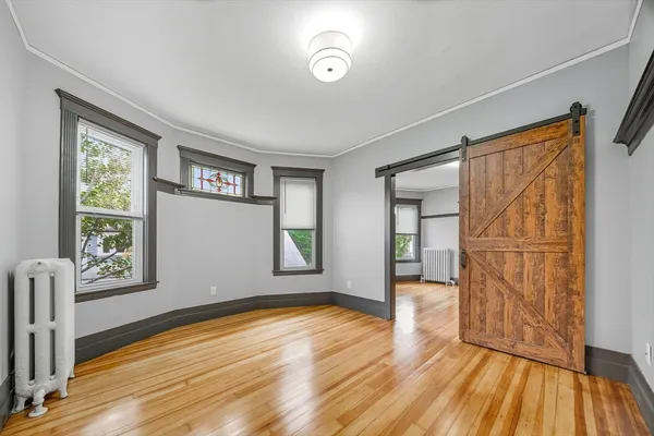 an empty room with wooden floor and windows
