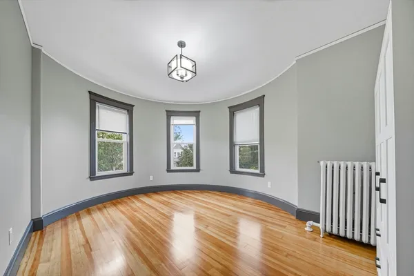 a view of empty room with a window and wooden floor