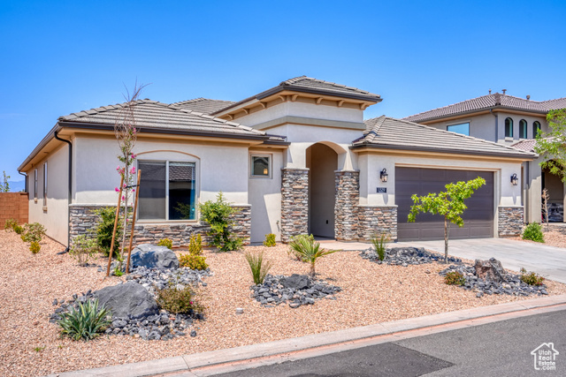 1329 Paseos Street Washington, UT 84780 - Photo 1 of 35 View of front facade with stone siding, driveway, an attached garage, stucco siding, and a tile roof