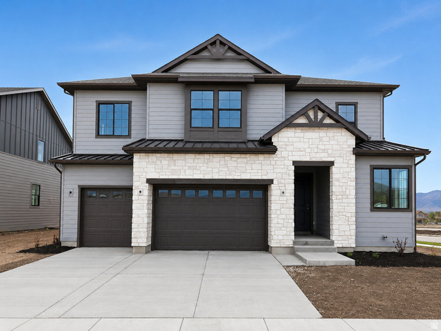 Contemporary two-story residence featuring light gray siding and white stone accents