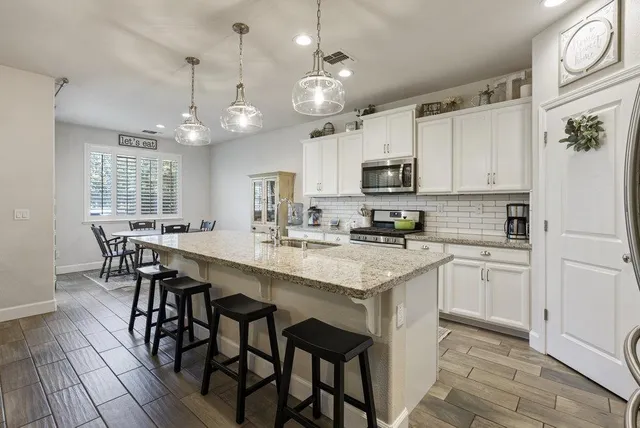 a kitchen with granite countertop white cabinets and stainless steel appliances