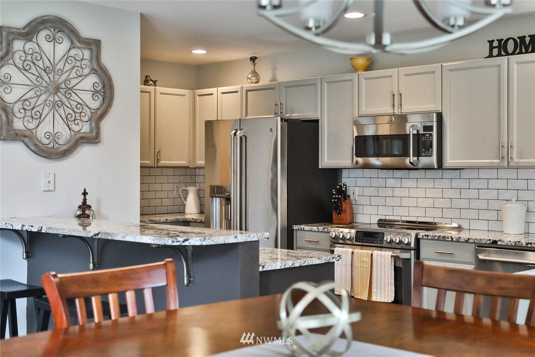 2432 195th Place Southeast, Unit B Bothell, WA 98012 - Photo 14 of 34 a kitchen with stainless steel appliances granite countertop a refrigerator a stove top oven a sink and dishwasher