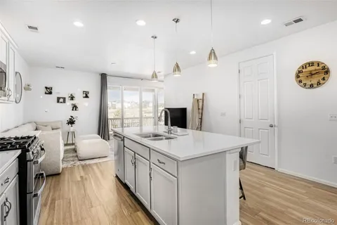a kitchen with a sink stove and wooden floor