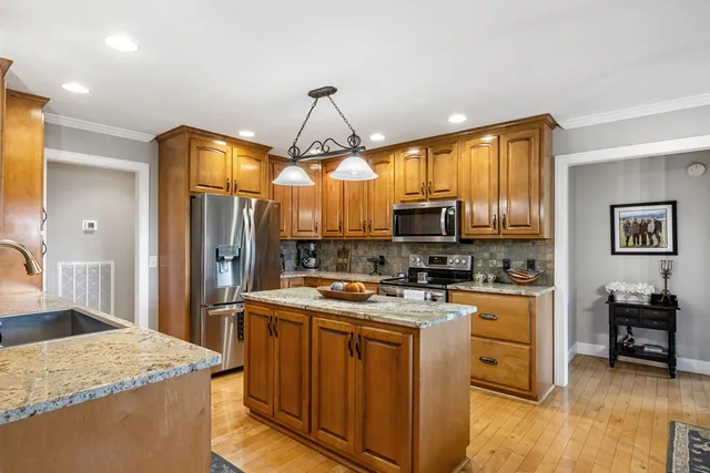 a kitchen with stainless steel appliances granite countertop a sink a stove and a wooden floors