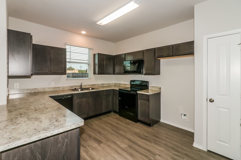 a kitchen with a refrigerator a sink a stove a microwave and wooden cabinets