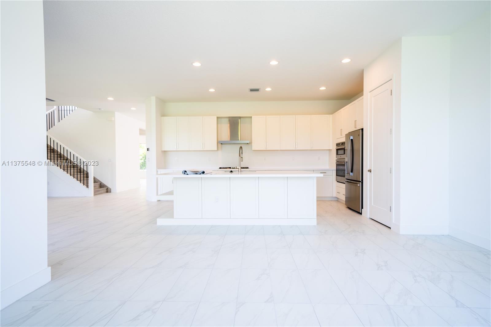 17232 Teton River Road Boca Raton, FL 33496 - Photo 6 of 28 a large white kitchen with stainless steel appliances kitchen island a stove a refrigerator a sink and a microwave