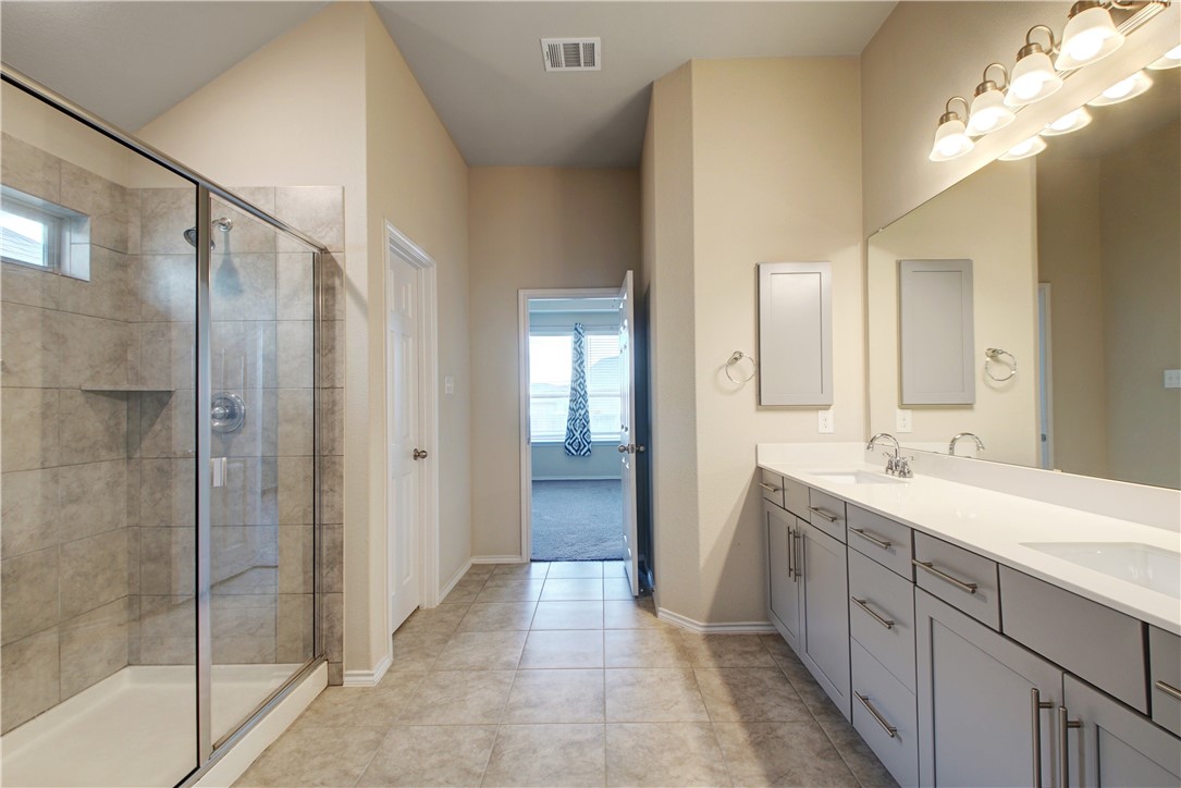 104 Finley Street Hutto, TX 78634 - Photo 16 of 37 a spacious bathroom with a shower sink and mirror