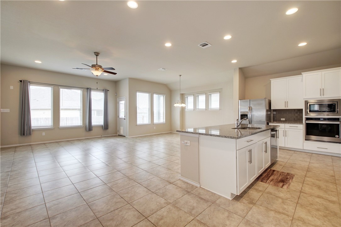 104 Finley Street Hutto, TX 78634 - Photo 3 of 37 a large kitchen with granite countertop a stove top oven a sink a counter space and cabinets