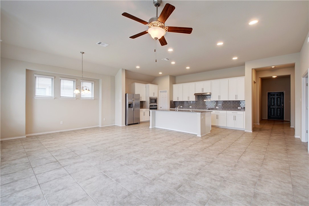 104 Finley Street Hutto, TX 78634 - Photo 6 of 37 a view of a kitchen with kitchen island a sink chandelier and refrigerator