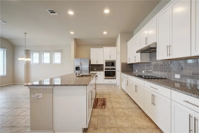 a large kitchen with stainless steel appliances kitchen island granite countertop a sink and cabinets