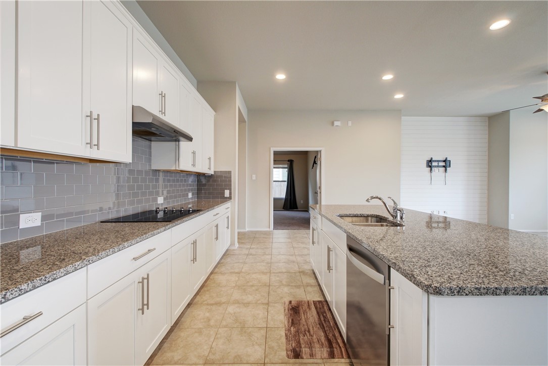 104 Finley Street Hutto, TX 78634 - Photo 8 of 37 a large kitchen with granite countertop a sink and dishwasher a stove with wooden floor