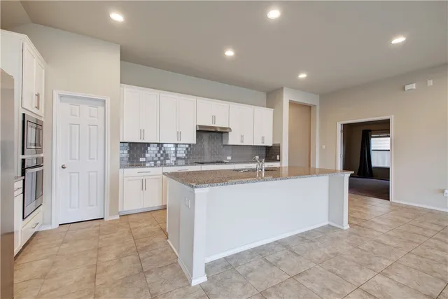 a large white kitchen with cabinets