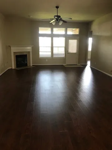 an empty room with wooden floor fireplace and windows