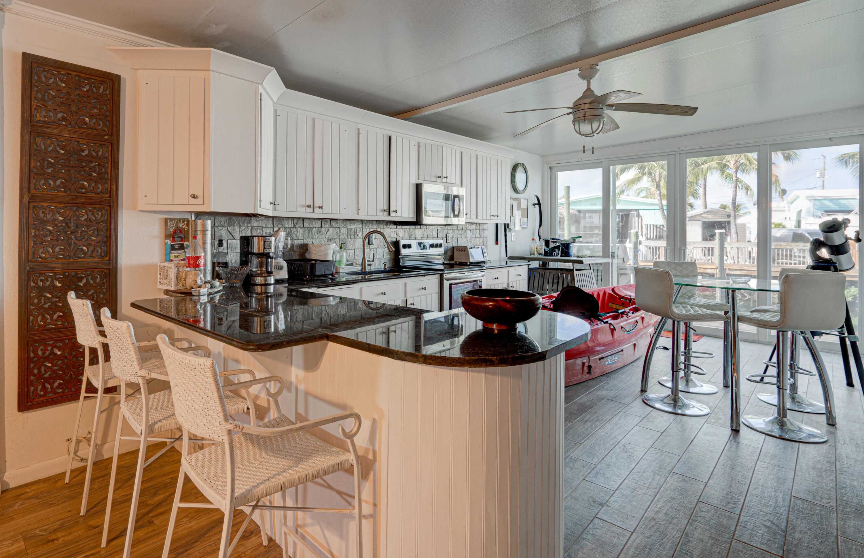 1361 Overseas Highway, Unit E11 Marathon, FL 33050 - Photo 19 of 46 a kitchen with stainless steel appliances kitchen island granite countertop a stove a sink a dining table and chairs with wooden floor