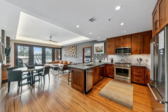 a kitchen with stainless steel appliances granite countertop wooden floors a stove and a refrigerator