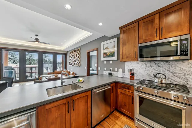 a kitchen with stainless steel appliances a sink dishwasher stove microwave refrigerator and cabinets