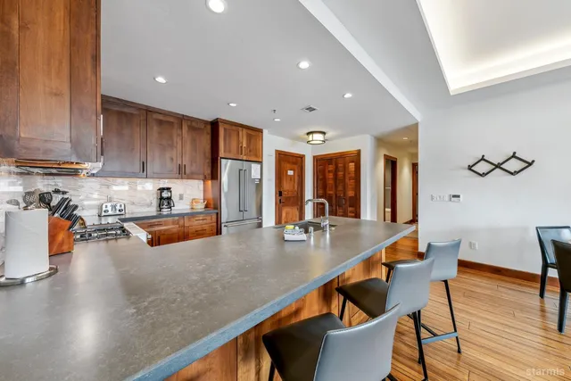 wooden kitchen with stainless steel appliances granite countertop a sink counter space and living room