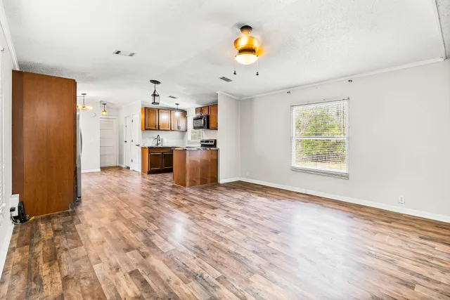 an empty room with kitchen appliances and wooden floor