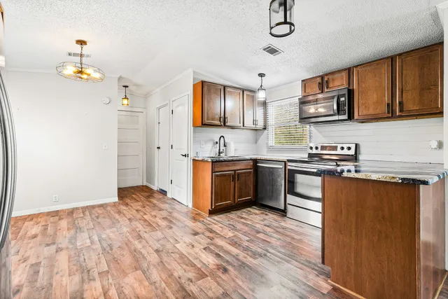 a kitchen with stainless steel appliances granite countertop a stove a sink and a refrigerator