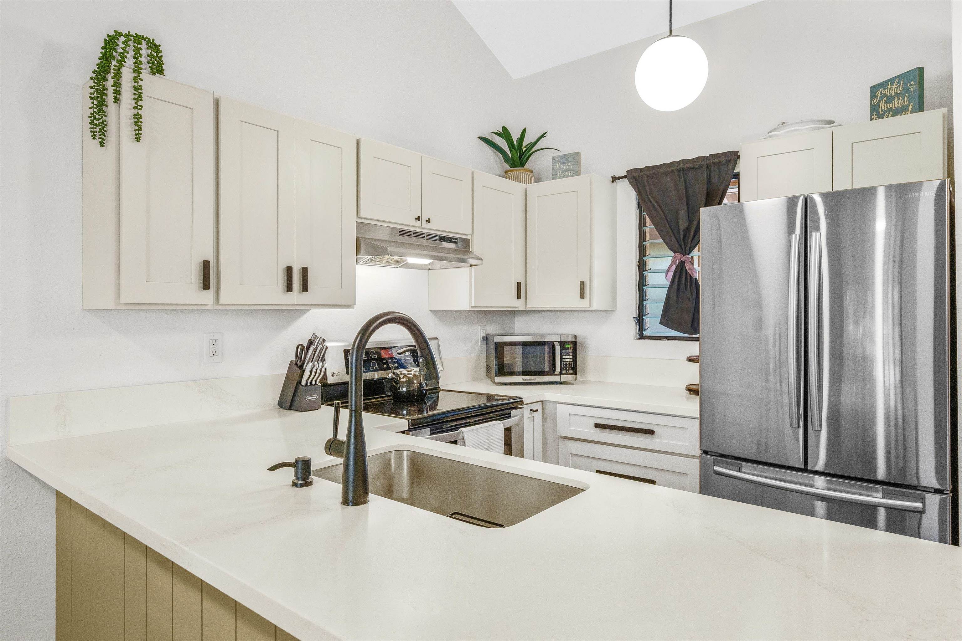 a kitchen with stainless steel appliances granite countertop a sink a stove and a refrigerator with white cabinets