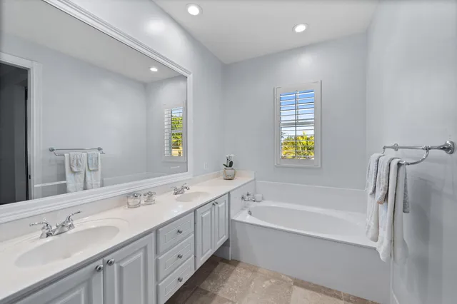 a spacious bathroom with a tub sink and mirror