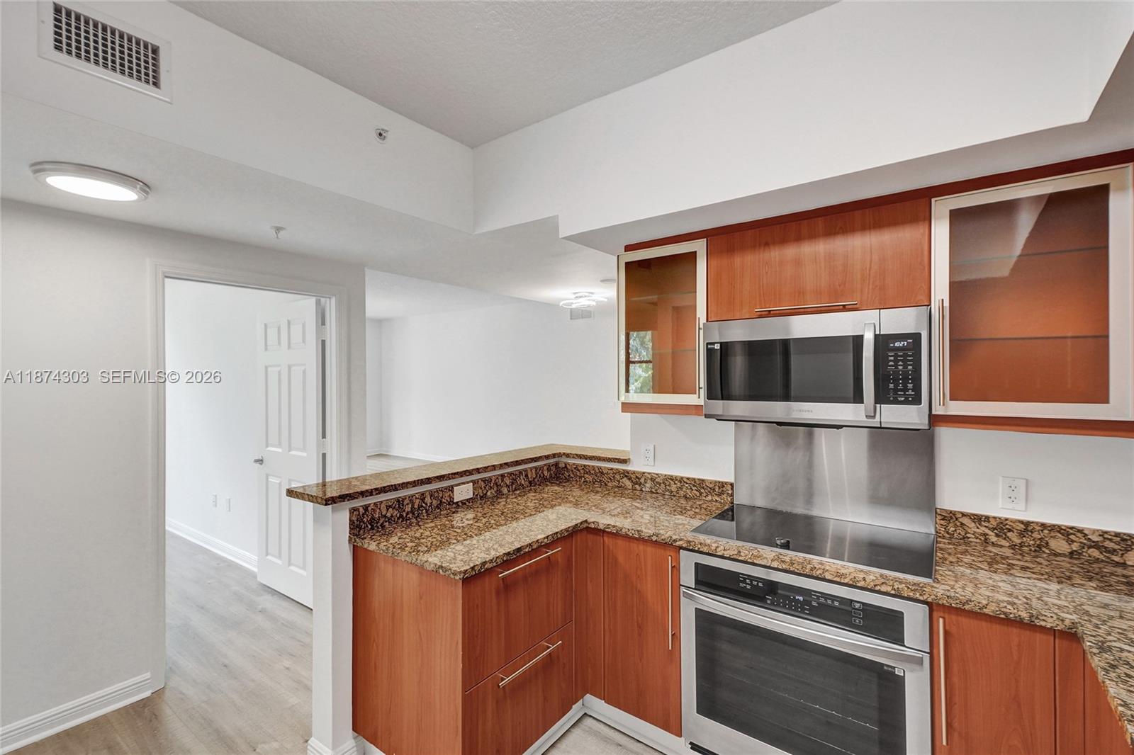 888 Douglas Road, Unit 304 Coral Gables, FL 33134 - Photo 14 of 52 a kitchen with stainless steel appliances granite countertop a stove and a microwave
