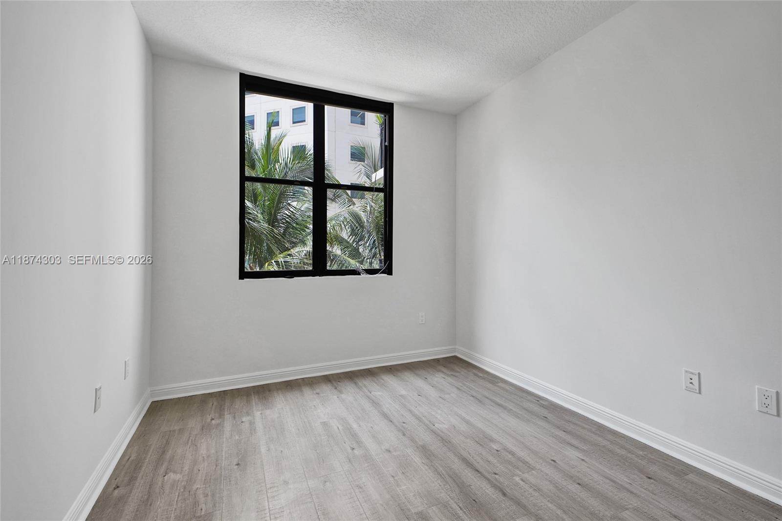 888 Douglas Road, Unit 304 Coral Gables, FL 33134 - Photo 17 of 52 an empty room with wooden floor and windows