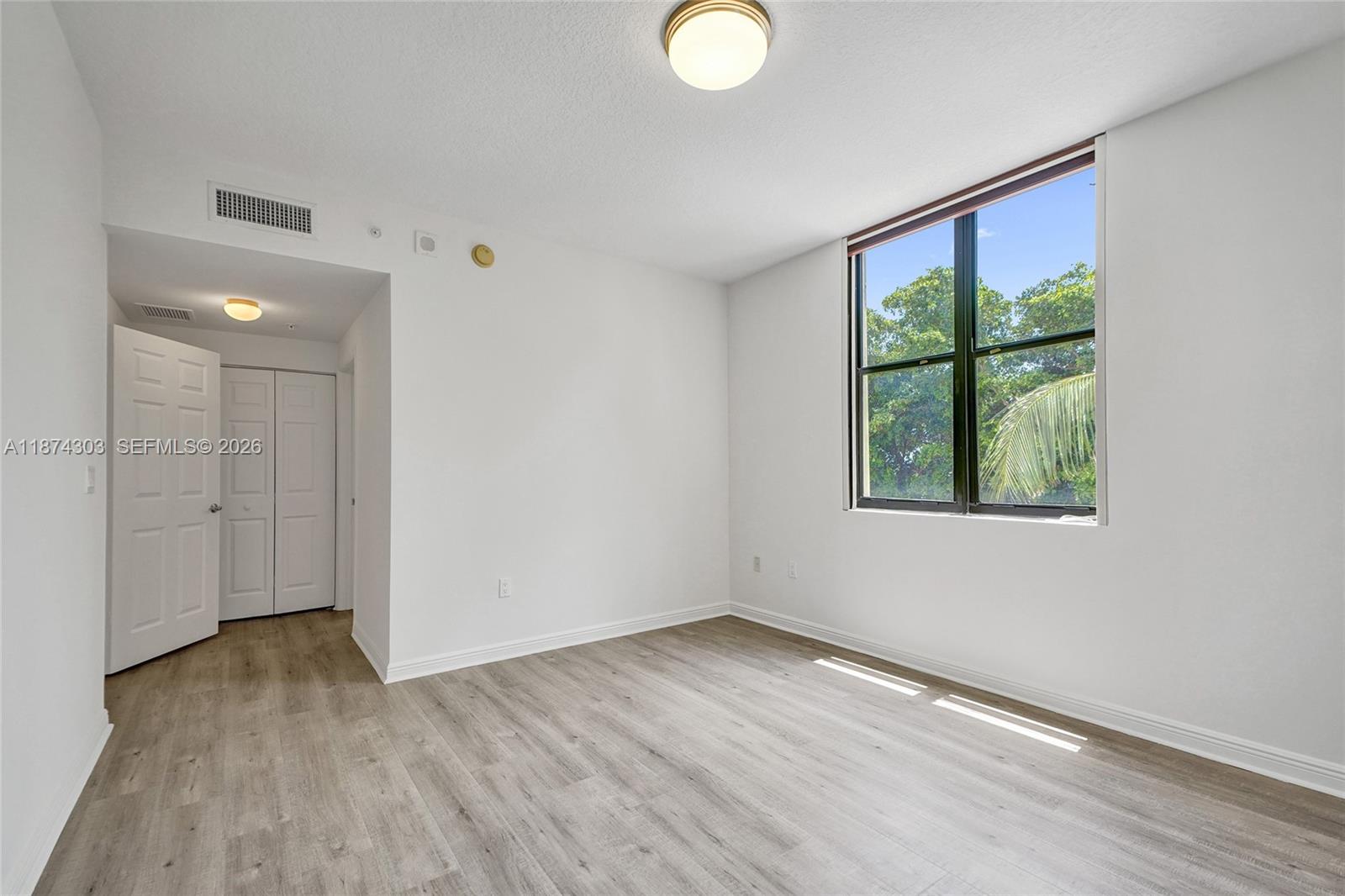 888 Douglas Road, Unit 304 Coral Gables, FL 33134 - Photo 22 of 52 a view of an empty room with wooden floor and windows