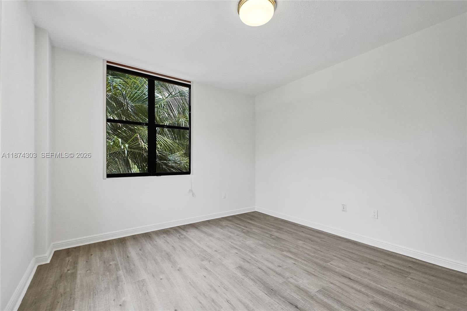 888 Douglas Road, Unit 304 Coral Gables, FL 33134 - Photo 24 of 52 an empty room with wooden floor and windows