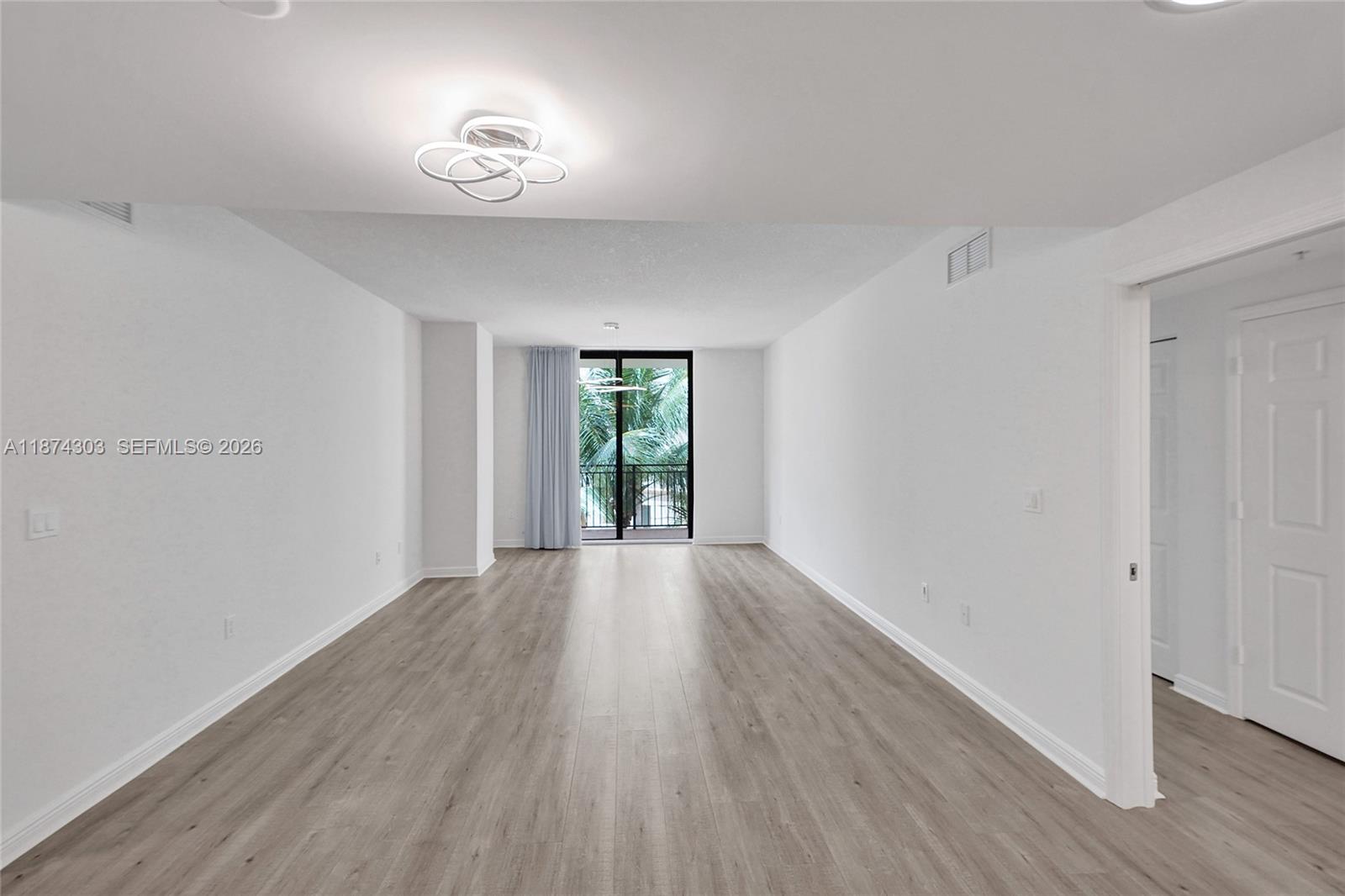 888 Douglas Road, Unit 304 Coral Gables, FL 33134 - Photo 6 of 52 a view of an empty room with wooden floor and a window