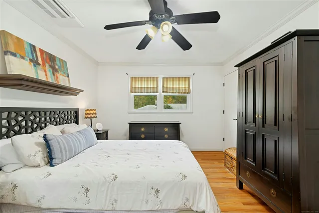 a bedroom with a large bed and a chandelier fan