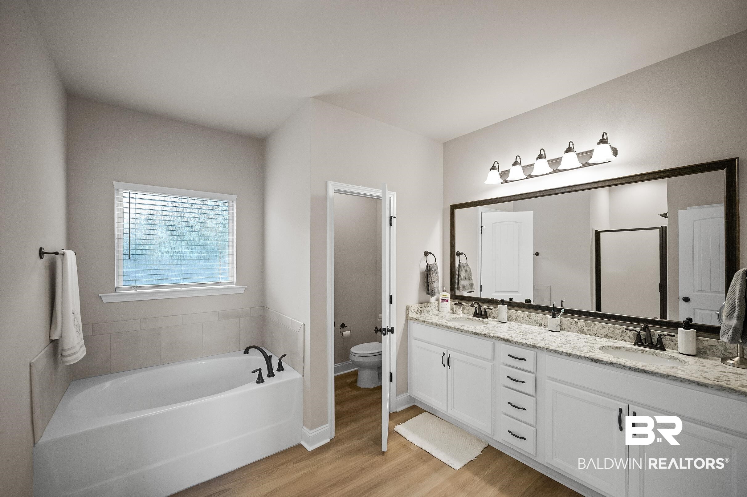 1077 Stella Road Foley, AL 36535 - Photo 6 of 27 Bathroom featuring a garden tub, double vanity, and light wood-style flooring