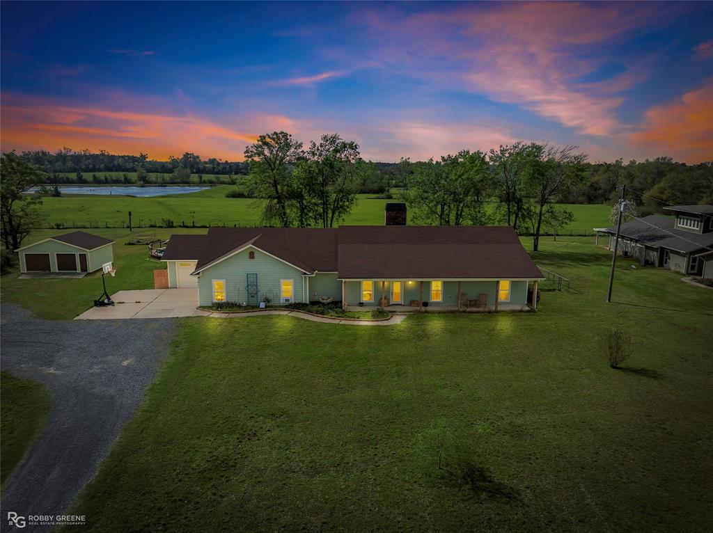 Ranch-style home featuring driveway, a front lawn, an outbuilding, a chimney, and a garage