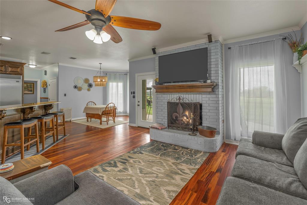 624 Holly Street Grand Cane, LA 71032 - Photo 3 of 40 Living room featuring crown molding, dark wood-style floors, ceiling fan, and a brick fireplace