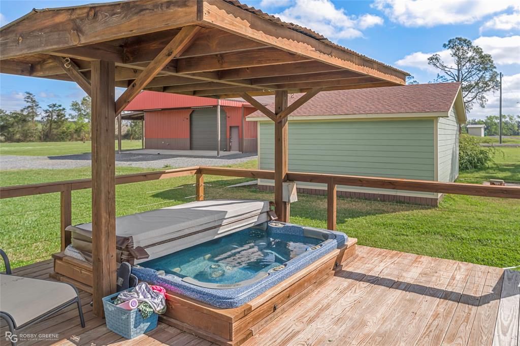 624 Holly Street Grand Cane, LA 71032 - Photo 36 of 40 Wooden terrace with a lawn, a covered hot tub, an outdoor structure, and a garage