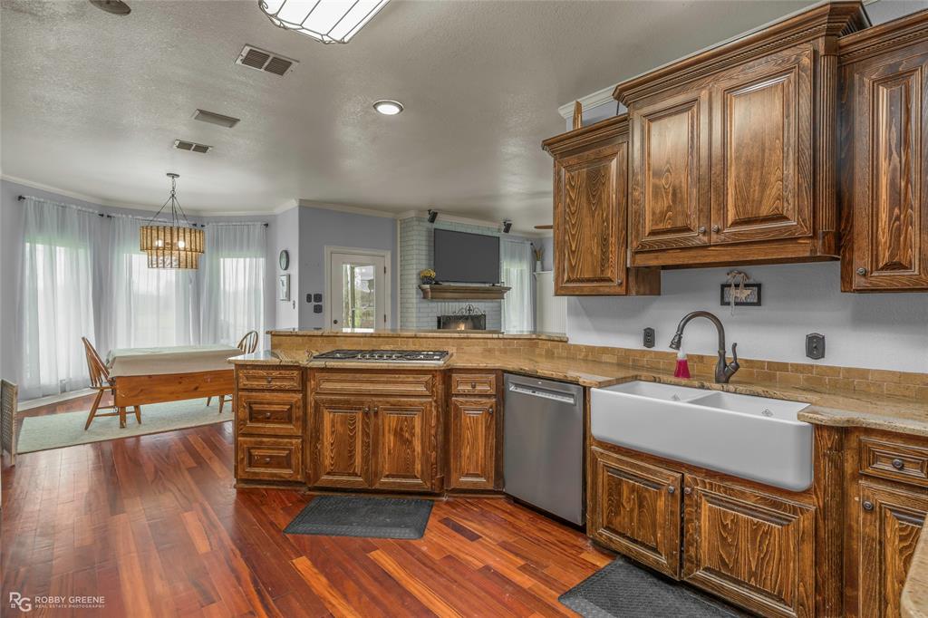 624 Holly Street Grand Cane, LA 71032 - Photo 9 of 40 Kitchen featuring crown molding, stainless steel appliances, dark wood-style flooring, a peninsula, and hanging light fixtures