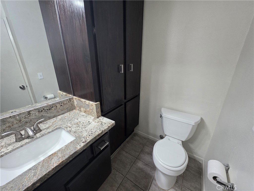 14839 Sherman Way, Unit 6 Van Nuys, CA 91405 - Photo 9 of 23 a bathroom with a granite countertop toilet sink and mirror