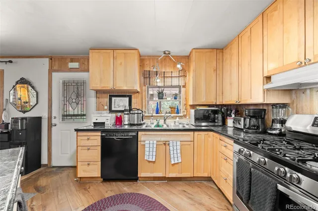 a kitchen with stainless steel appliances granite countertop a stove a sink dishwasher and cabinets with wooden floor